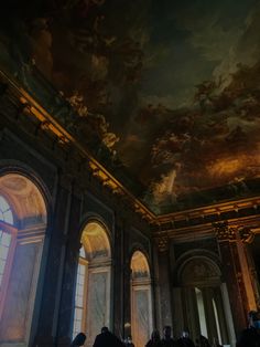 people are standing in an ornate room with paintings on the ceiling