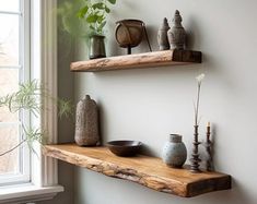 two wooden shelves with vases and other items on them in front of a window