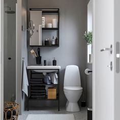 a white toilet sitting next to a sink in a bathroom under a mirror on the wall