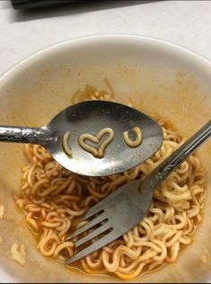 two forks are stuck into some noodles with the word love spelled on them in a bowl