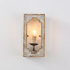 a wall mounted light with a candle in the middle and a mirror on the side