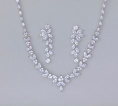 a necklace and earring set with diamonds on the bottom, along with a pair of earrings