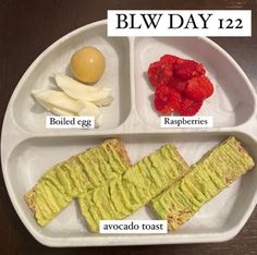 a white plate topped with food on top of a wooden table next to an egg, raspberries and avocado toast