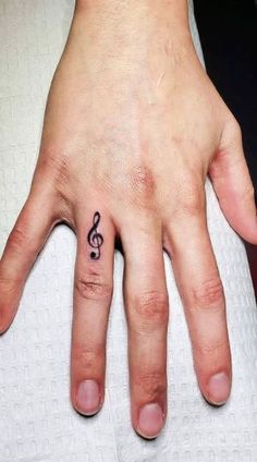 a hand with a musical note tattoo on it's left thumb and ring finger