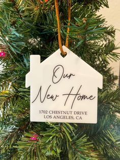 a house ornament hanging on a christmas tree with the words our new home