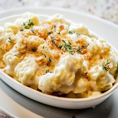 a white bowl filled with macaroni and cheese on top of a plate next to a fork