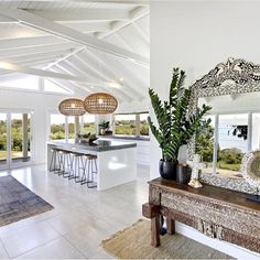 an open concept kitchen and dining room with white walls, wood floors and ceiling beams