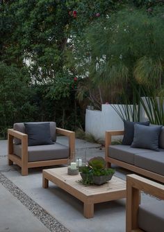 an outdoor living area with couches, tables and plants in the middle of it