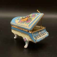 an ornate blue and yellow musical box with piano keys on it's sides, sitting on a black surface