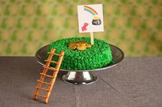 a cake with green grass and gold coins on top, next to a miniature ladder