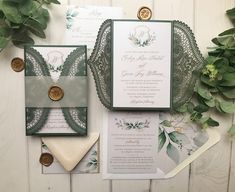 the wedding stationery is laid out next to some greenery