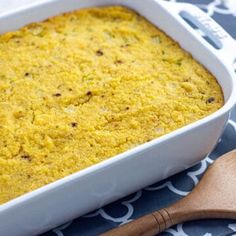 a casserole dish with bread in it and a wooden spoon on the side