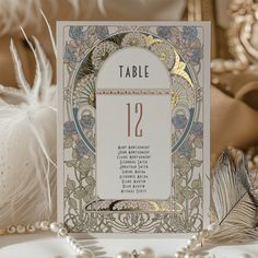 a table number card sitting on top of a table next to some pearls and feathers