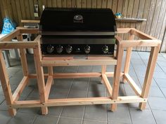 an outdoor bbq grill with three burners and two side tables made out of wood