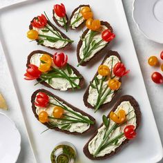 several pieces of bread with cream cheese and vegetables on them sitting on a white plate