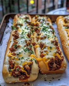 two long hot dogs with cheese and meat on them