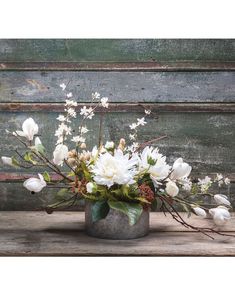 a vase filled with white flowers on top of a wooden table