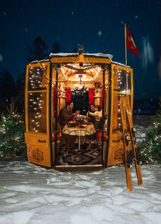 two people sitting at a table in the back of a bus with christmas lights on it