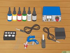 the contents of a tattoo machine laid out on a wooden table with markers, ink bottles and other items