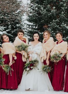 the bride and her bridesmaids are dressed in red dresses with fur stoles