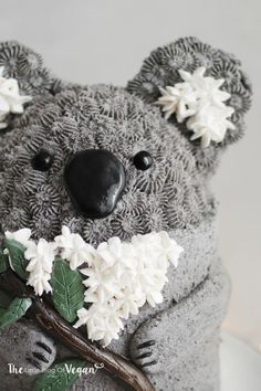 there is a cake made to look like a koala bear with flowers on it