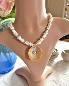 Dive into summer elegance with our exquisite necklace, a harmonious blend of white seashell chips, lustrous white freshwater pearls, and sparkling Charlotte-cut Czech glass beads. At its heart lies a stunning limpet shell adorned with a captivating white freshwater pearl centerpiece. Measuring approximately 40 cm (16 inches) with a 5 cm extension chain, this one-of-a-kind (OOAK) piece captures the allure of the oceanic theme and is perfectly on-trend for the summer of 2024.  Whether you're dress Vacation Pearl Shell Necklace, Pearl Shell Necklace For Vacation, Beach Pearl Necklace With Pearl Pendant, Pearl Pendant Shell Necklace For Beach, White Shell-shaped Pearl Drop Necklace, Elegant Beach Pearl Shell Pendant, Elegant Pearl Pendant Shell For Beach, White Shell Necklace With Pearl Pendant As Gift, Pearl Pendant Necklace For Beach