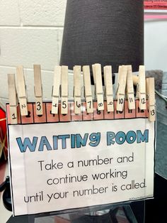 a sign that says waiting room on the side of a desk with clothes pins attached to it