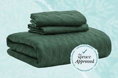 two green bedspreads stacked on top of each other in front of a blue background