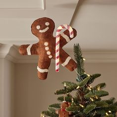 a gingerbread christmas ornament hanging from the ceiling next to a small tree