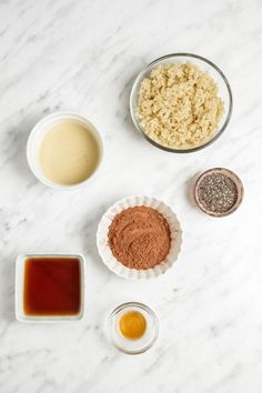 ingredients to make chocolate cake laid out on a white marble counter top, including eggs, sugar, and syrup