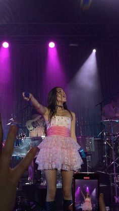 a woman in a pink and white dress on stage