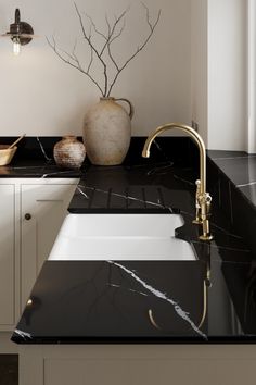 a black counter top with a white sink and gold faucet next to it