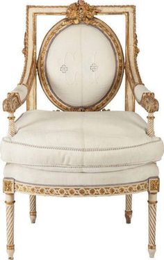 an ornately decorated chair with white fabric and gold trim