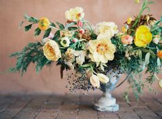 a vase filled with lots of flowers on top of a brick floor