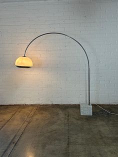 a lamp that is on top of a floor next to a brick wall and concrete floor