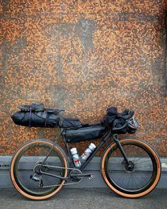 a bicycle parked next to a wall with bags on the front and back tire,