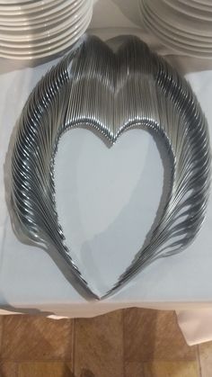 a heart shaped metal object sitting on top of a table covered in plates and napkins