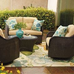 an outdoor living room with wicker furniture and blue vase on the table in front of it