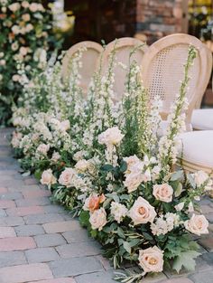 several chairs lined up with flowers and greenery