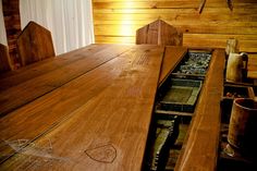 a wooden table and chairs in a room with wood paneling on the wall behind it