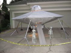 two alien figures are standing in front of a house with a large metal structure on it's roof