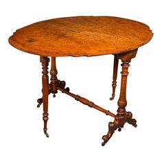 an old wooden table with two legs and a round top on wheels, in the shape of a leaf