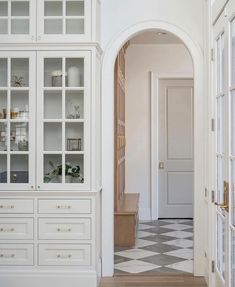 the interior of a house with white walls and flooring, including an arched doorway