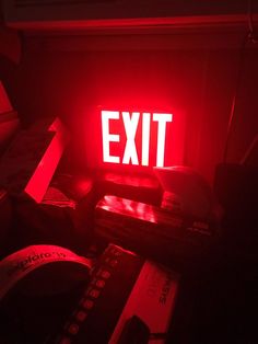 a red exit sign sitting on top of a table next to remotes and boxes