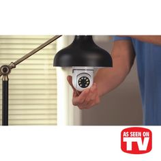 a person holding a camera in their hand with the tv logo on it and an image of a lamp behind them