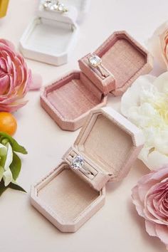 three wedding rings are sitting in their boxes next to flowers