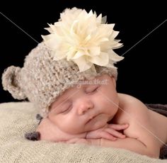 a newborn baby wearing a knitted hat with a flower on top