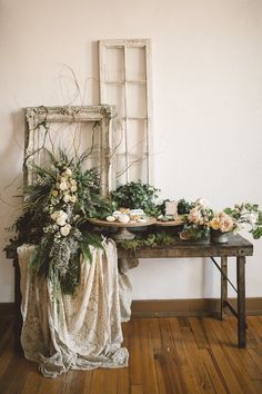 a table topped with flowers and greenery next to an old wooden window sill