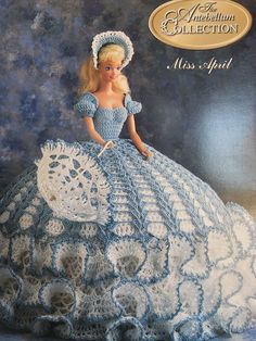 a crocheted doll in a blue dress with an umbrella