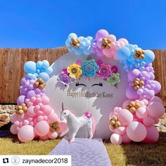 a unicorn is standing in front of a birthday backdrop with balloons and flowers on it